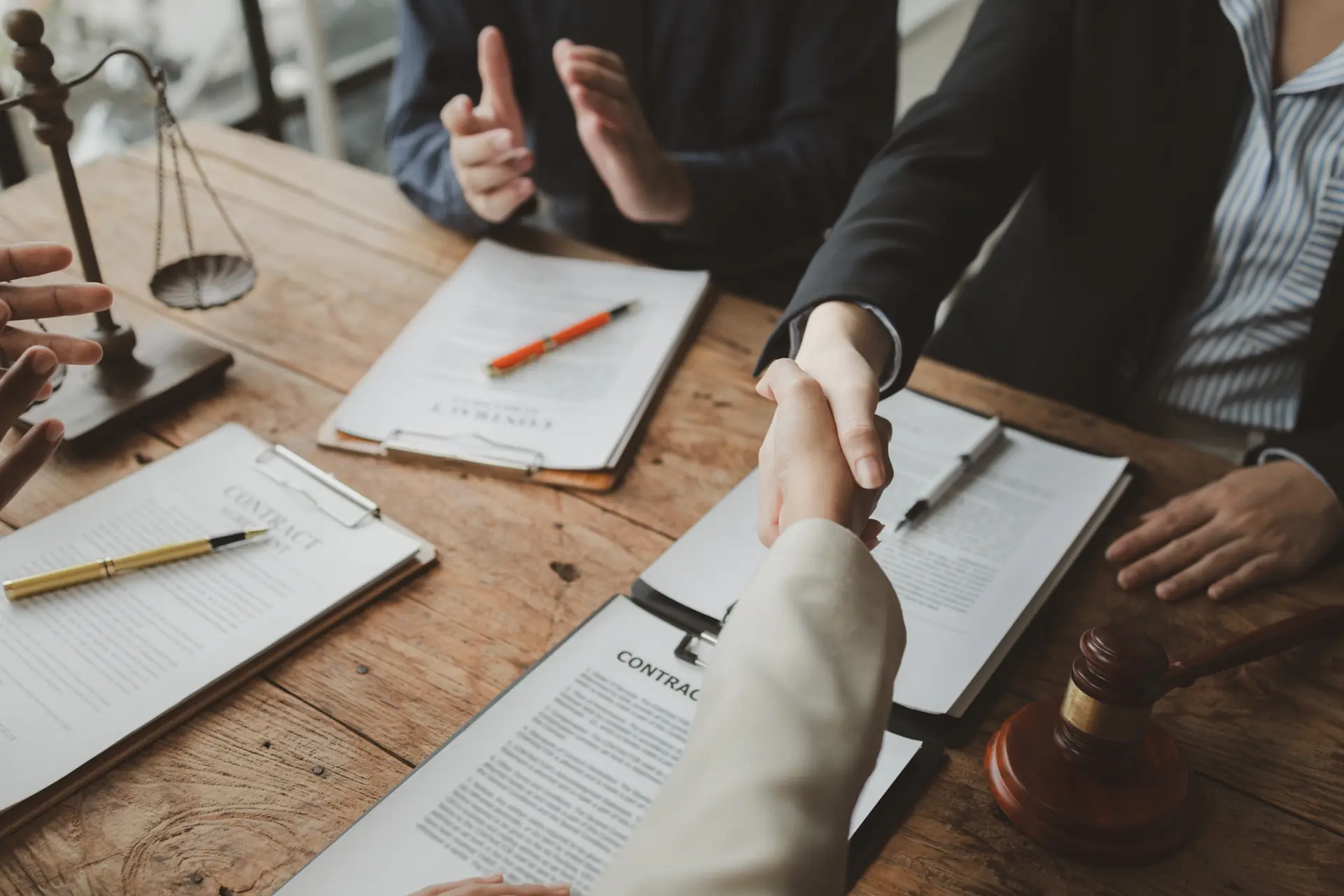 Business owners shaking hands over signed contract with scales of justice at Garrett County law firm