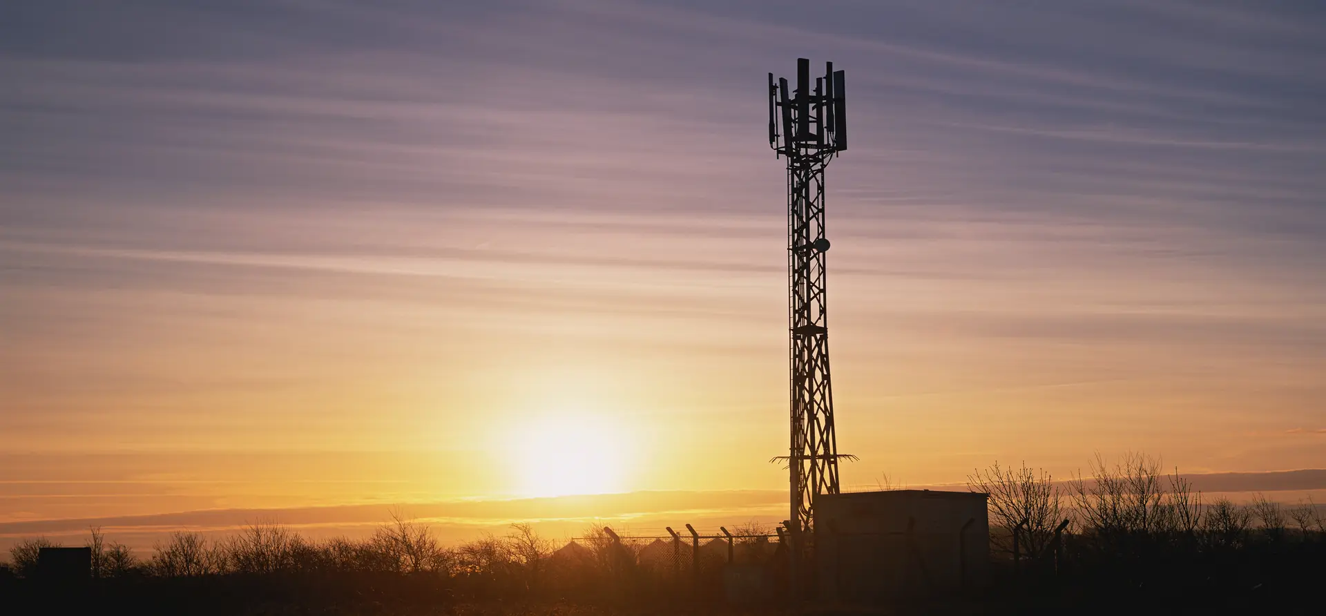 Cell tower silhouette at sunset on rural Western Maryland farmland representing telecom lease agreements